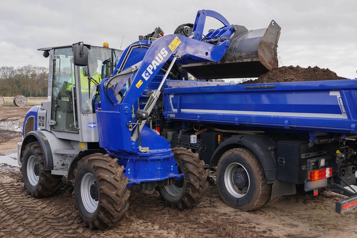 Seitliches Verladen von Baumaterial auf einen LKW auf einer GaLaBau-Baustelle